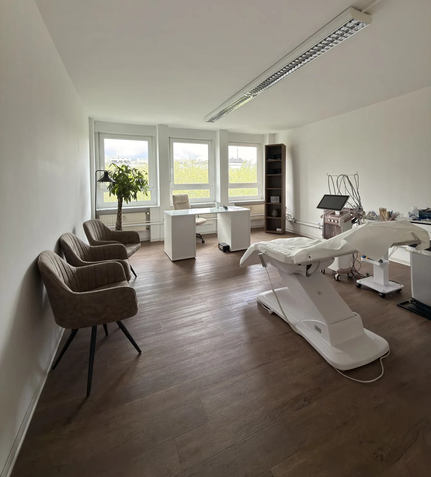 Heller Behandlungsraum von KÖ-PHYSIO mit Therapieliege und Sitzbereich
