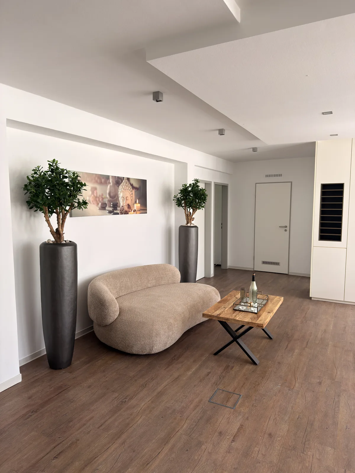 Ruhiger Empfangsbereich von KÖ-PHYSIO mit Sofa, Pflanzen und warmem Holzboden