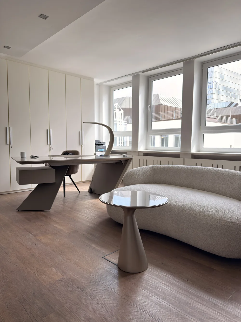 Gesprächsbereich von KÖ-PHYSIO mit rundem Tisch, Sofa und Fensterfront